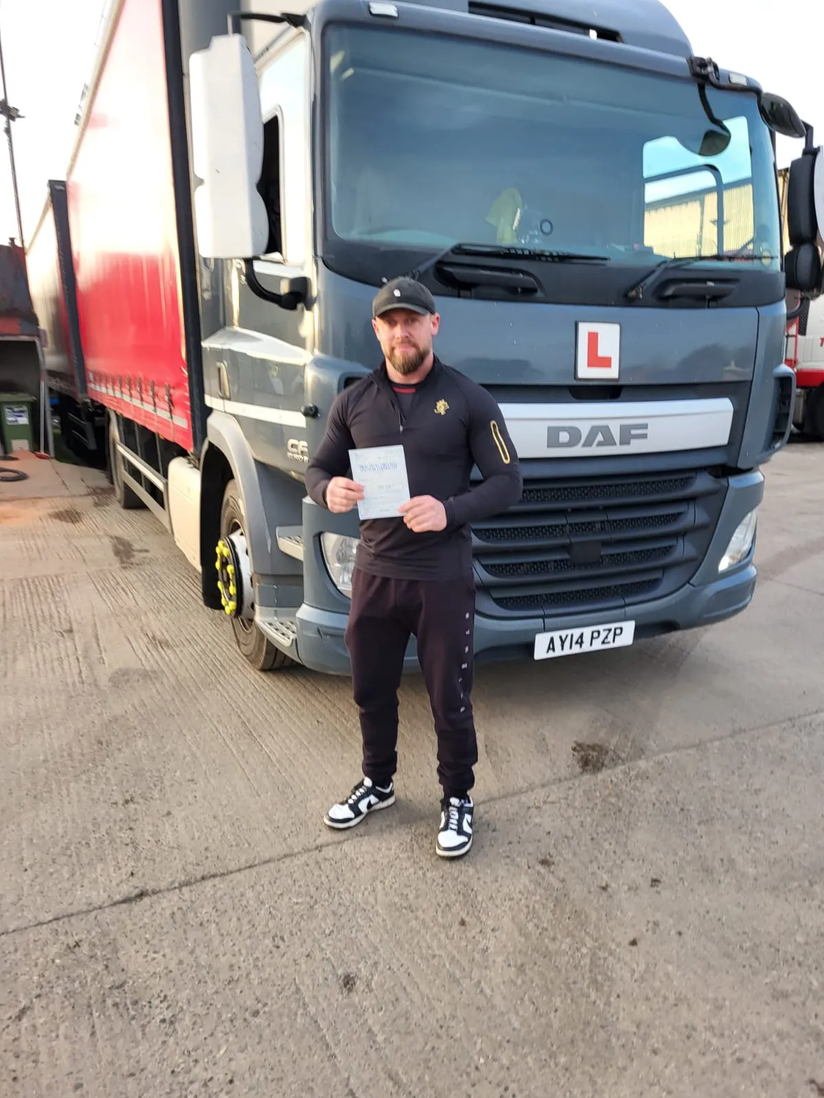 A man standing in front of a truck holding a piece of paper.